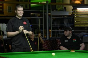 Archie Buskin smiles as he prepares to play a snooker shot