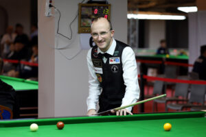 Daniel Blunn smiles at the camera before playing a snooker shot