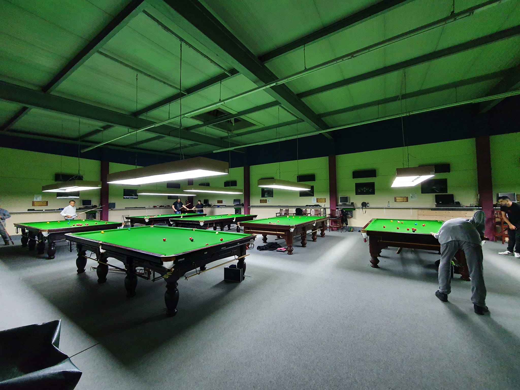 People playing snooker on six tables