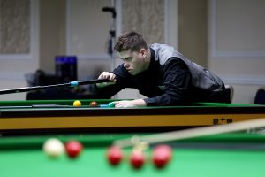 Archie Buskin plays a snooker shot with the rest