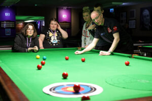 Coach Andrew Highfield leads one of the activities which involves rolling a snooker ball down the snooker table and onto a archery style target