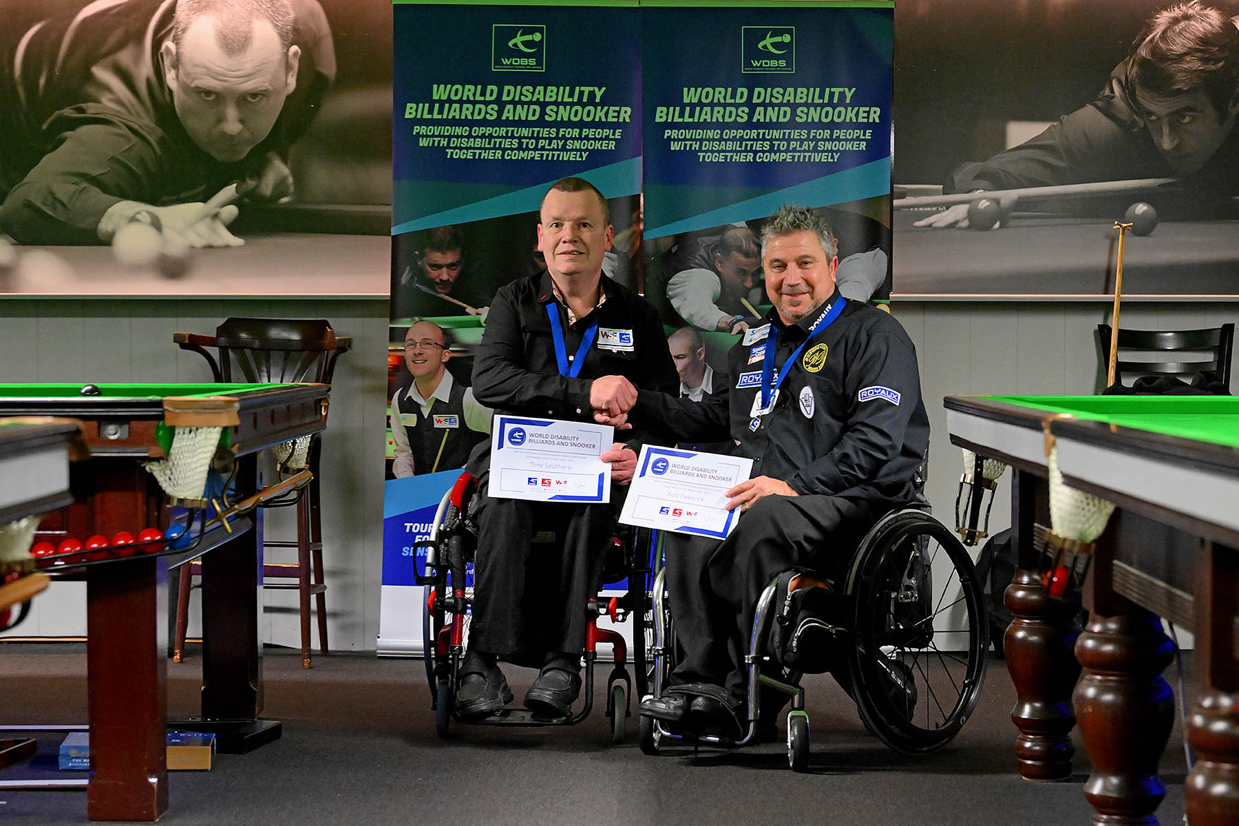 Two wheelchair users shaking hands with certificates