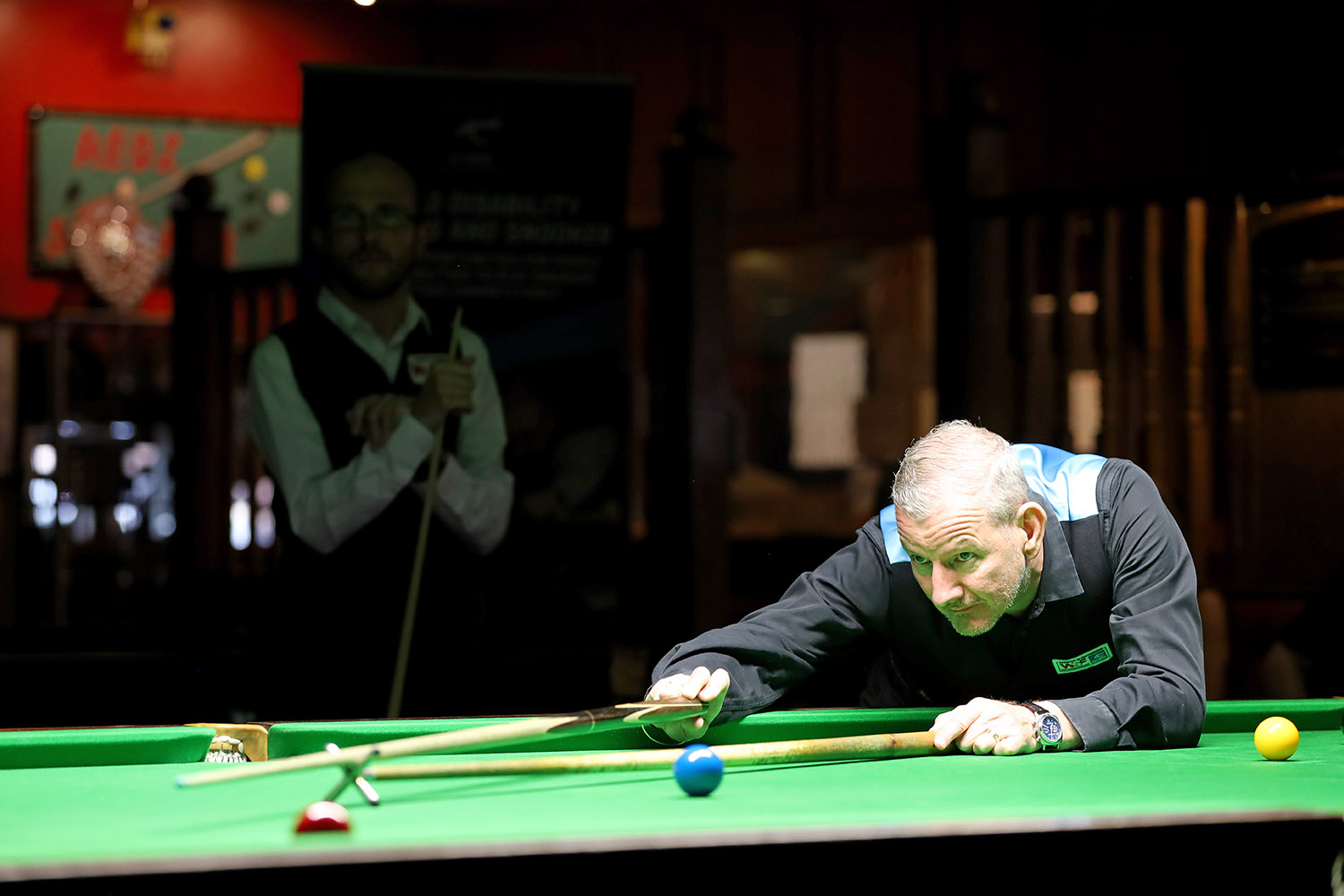 Gary Taylor plays snooker shot with Daniel Blunn in background